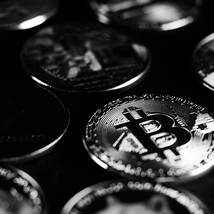 Monochrome close-up shot of Bitcoin and cryptocurrency coins, capturing digital currency essence.